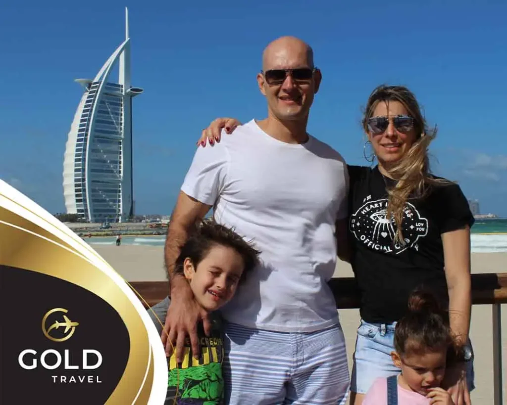 Familia sonriendo en Dubái con el hotel Burj Al Arab de fondo, viaje organizado con Gold Travel